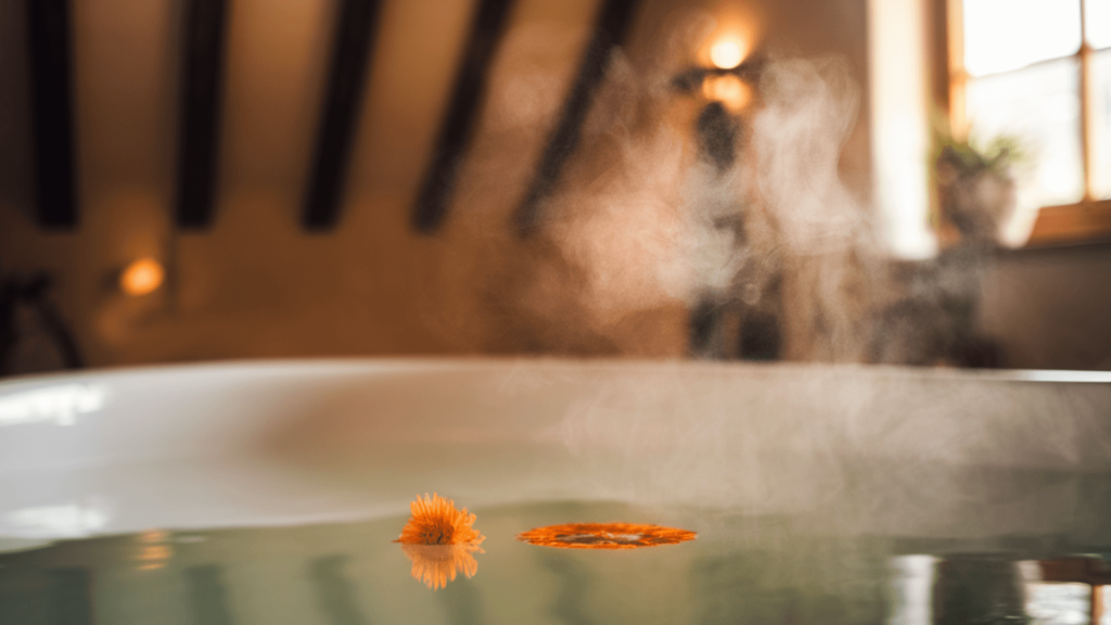 a bathtub filled with warm water, a single calendula flower floating on the surface, steam rising, soft warm lighting